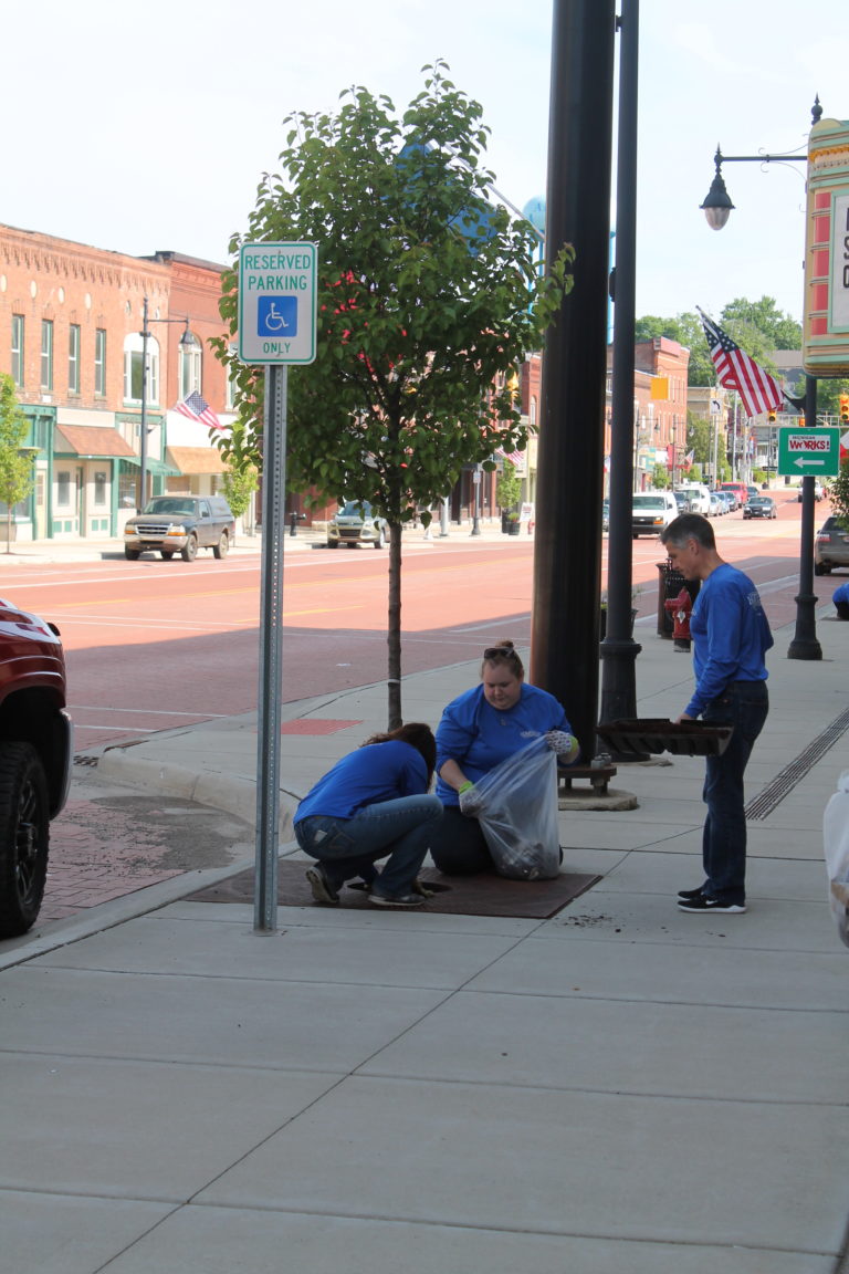 Three members of the Homestead team replacing mulch for a tree in downtown Albion.