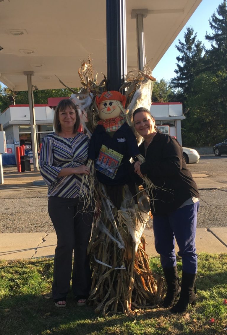 Homestead Savings Bank workers posing next to a scarecrow posted up an a lamppost in Leslie, Michigan.